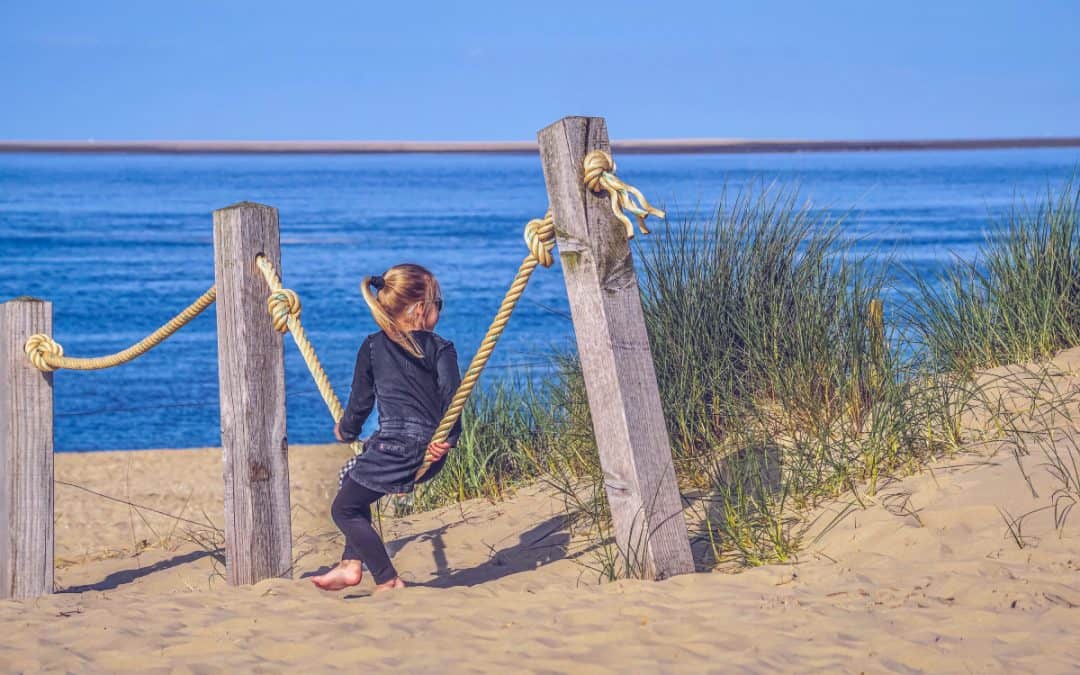 Kind sitzt auf der Schaukel am Meer