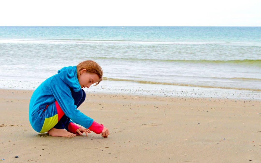 Ein Kind spielt Solitär im Sand